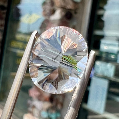 A loose, faceted oval laser cut pinkish white petalite stone.