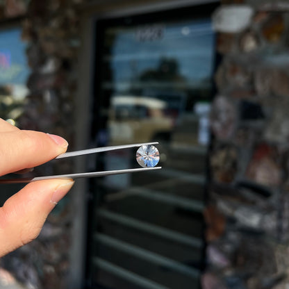 A round brilliant cut petalite gemstone.  The stone is colorless.