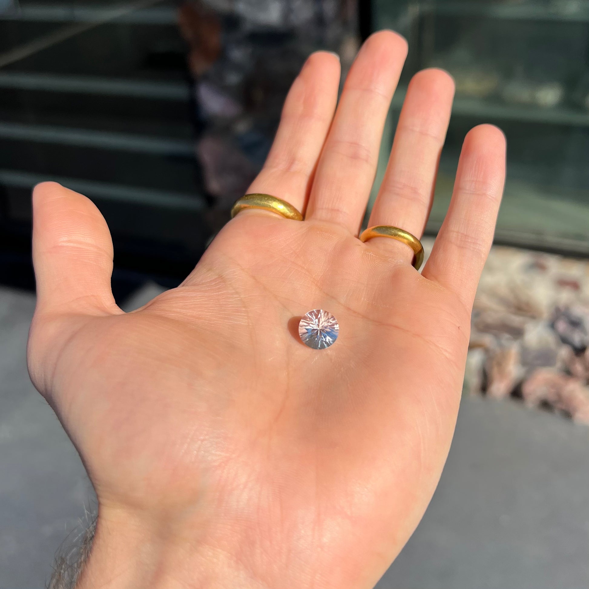 A round brilliant cut petalite gemstone.  The stone is colorless.