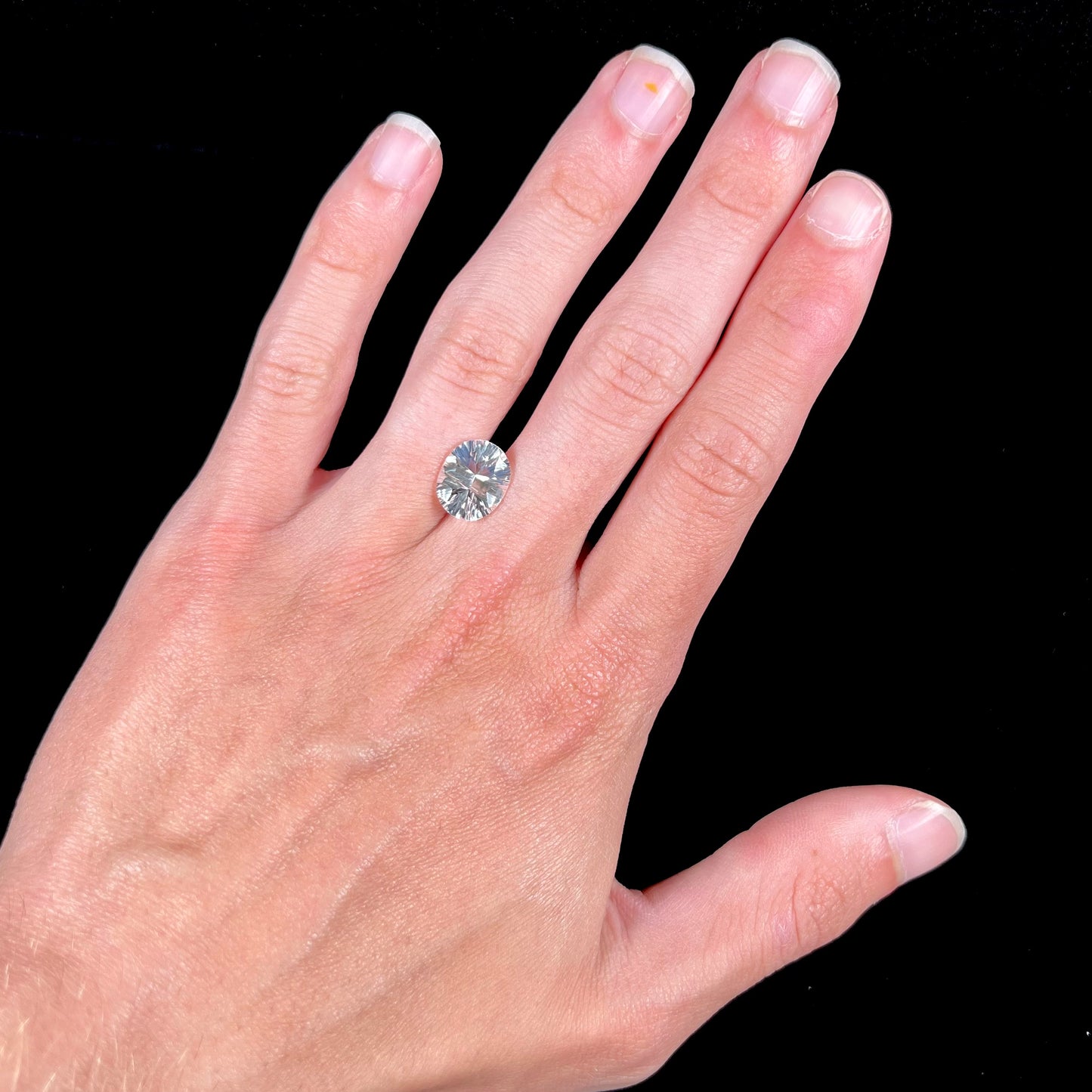 A loose, faceted oval laser cut pinkish white petalite stone.