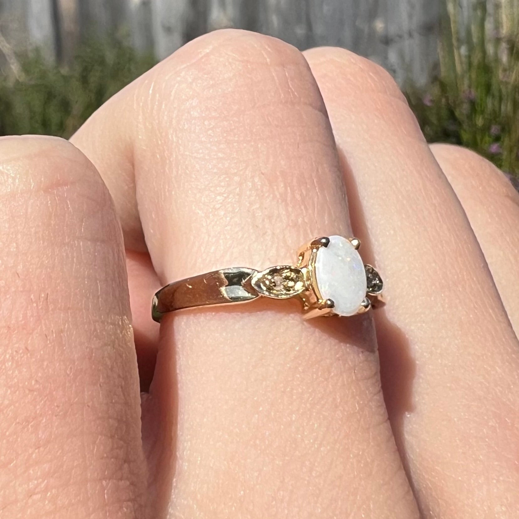 A dainty natural opal and diamond engagement ring in yellow gold.