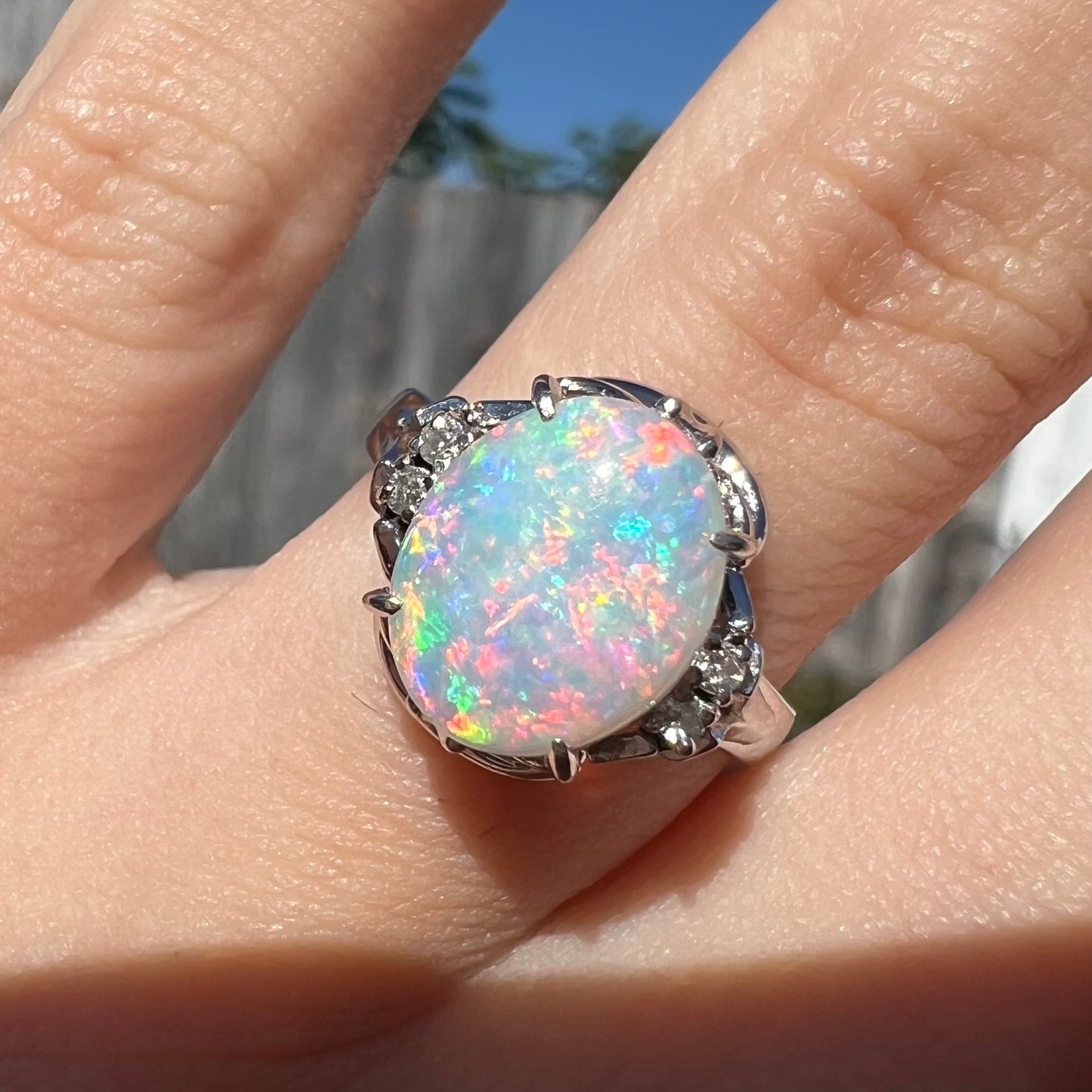 A platinum  and diamond ring prong-set with an Australian opal.  The opal has pink color play.