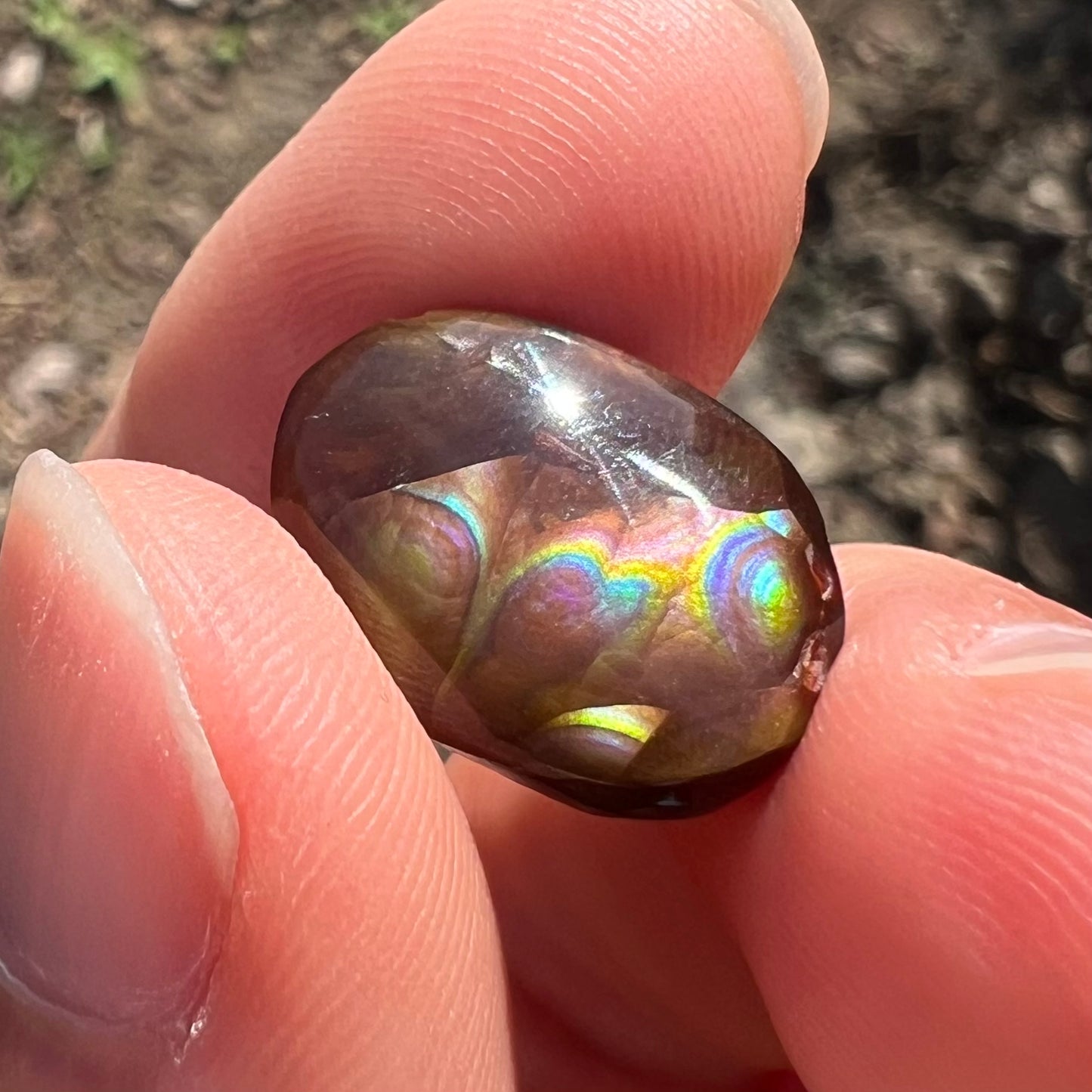 A loose, oval cabochon cut Mexican fire agate stone with pink, orange, and purple banding.