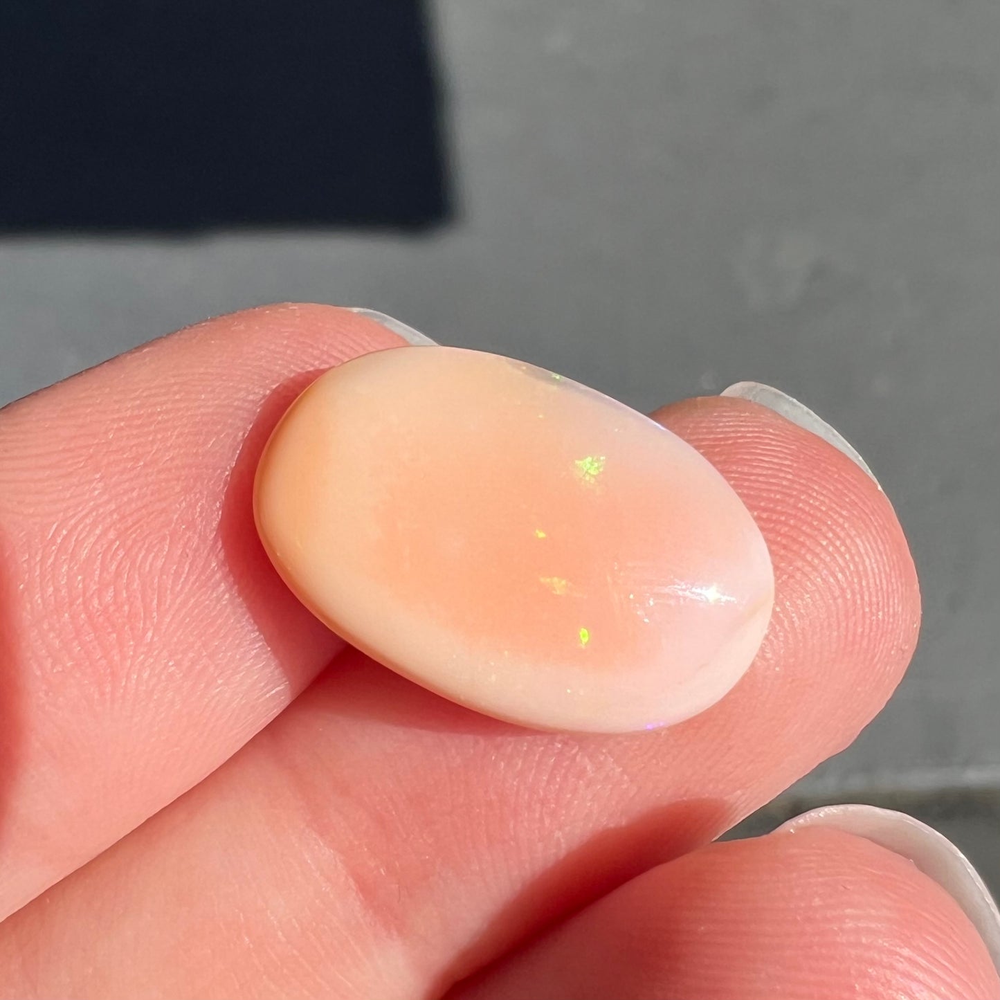 A loose, oval cabochon cut Peruvian opal stone.  The opal is a coral pink color.