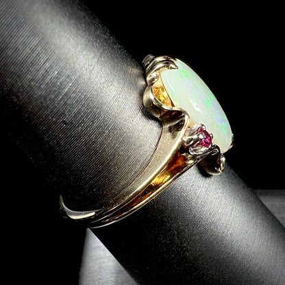 A 1920's Art Nouveau opal and pink sapphire ring.   The ring is yellow gold and palladium.  The opal is green and purple.