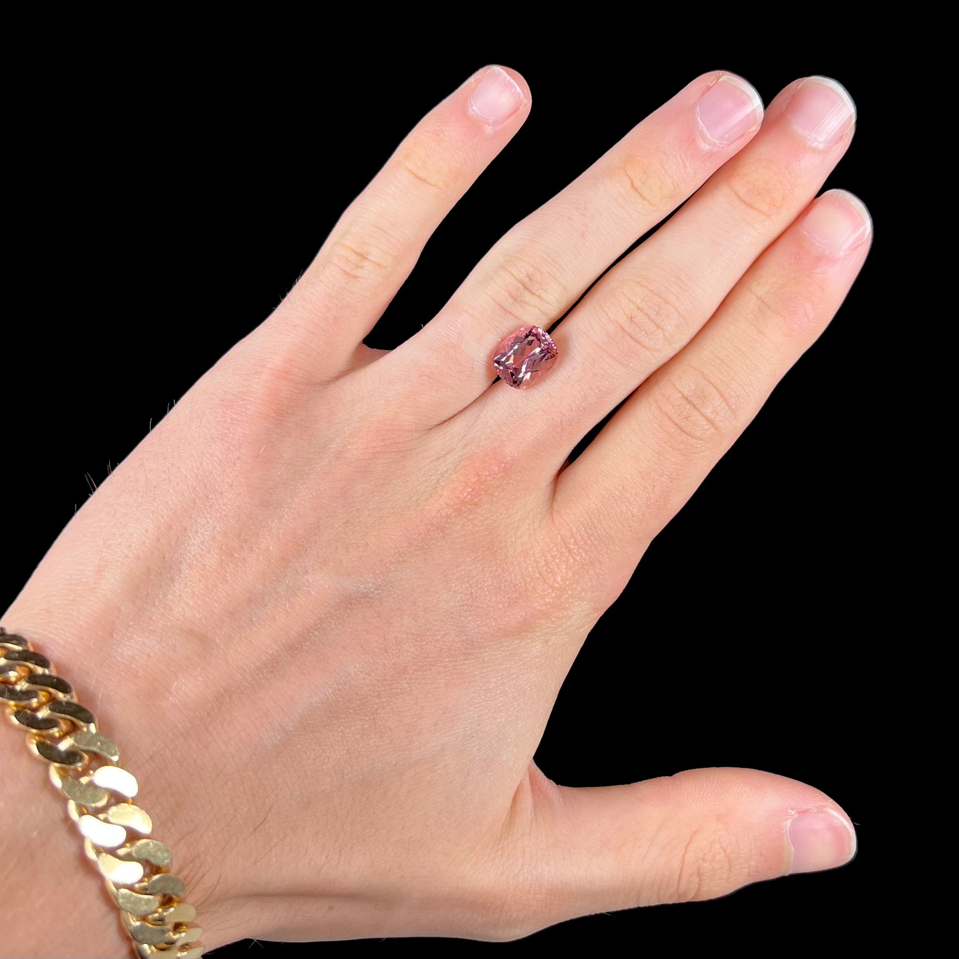 A loose, cushion cut light pink tourmaline gemstone.