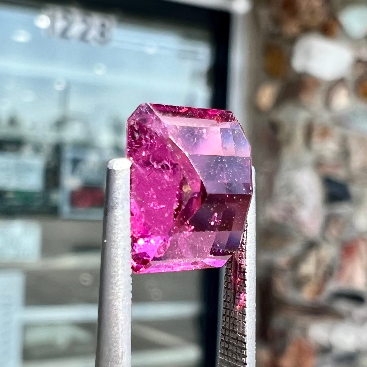 A loose, faceted modified emerald cut hot pink tourmaline stone.