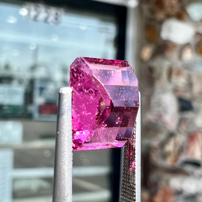 A loose, faceted modified emerald cut hot pink tourmaline stone.