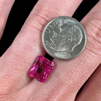 A loose, faceted modified emerald cut hot pink tourmaline stone.