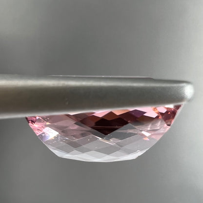 A loose, cushion cut light pink tourmaline gemstone.