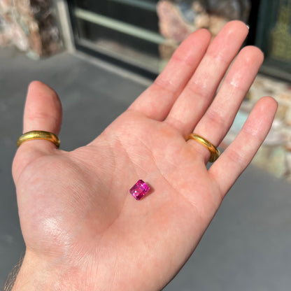 A loose, faceted modified emerald cut hot pink tourmaline stone.