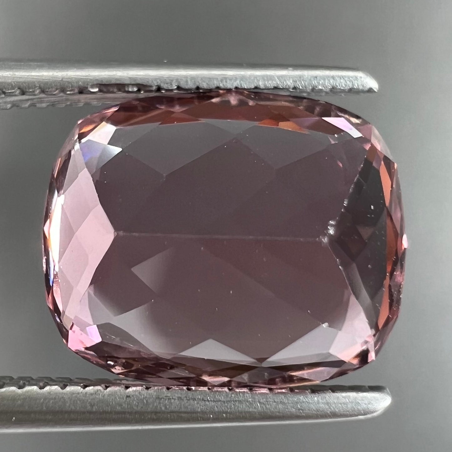 A loose, cushion cut light pink tourmaline gemstone.