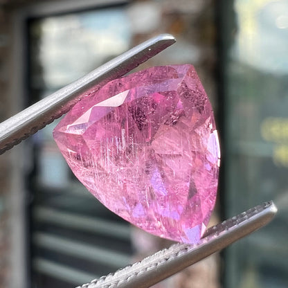 A loose, faceted trillion cut pink touramline gemstone.  The stone is a light bubblegum pink color.