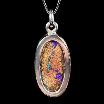 A handmade sterling silver pendant bezel set with an oval cut pipe boulder opal stone.