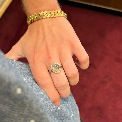 A silver Atocha 1 reale coin replica set in a yellow gold ring.