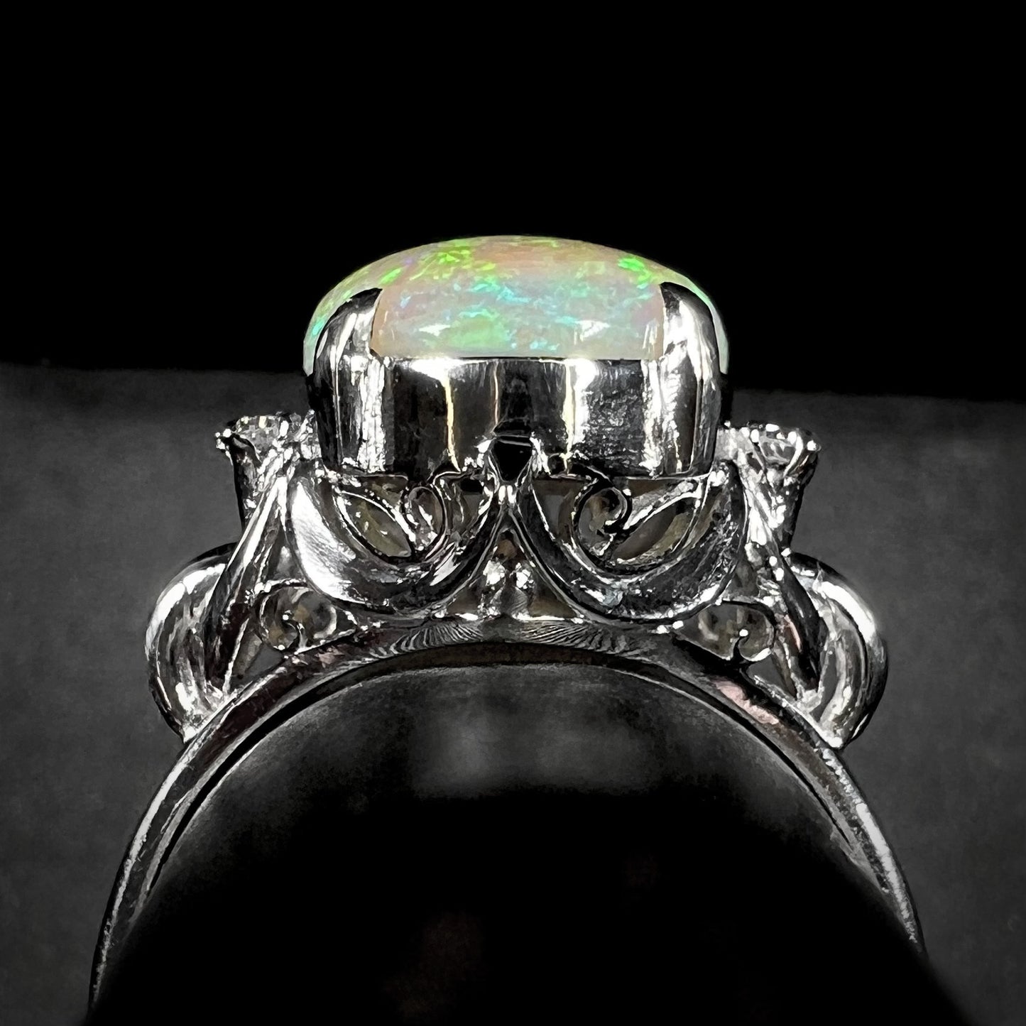 An Australian crystal opal and diamond engagement ring set in a platinum filigree mounting.  The opal plays green/blue colors and has a crack.