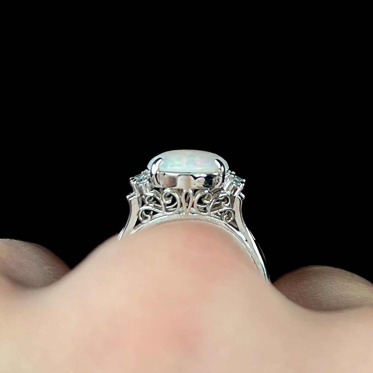 An Australian opal and diamond engagement ring in platinum.  The ring has filigree scrolling.