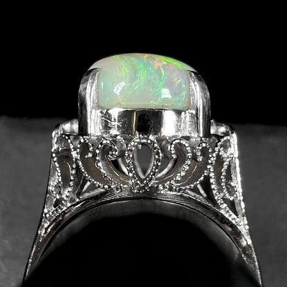 A ladies' Australian opal solitaire engagement ring mounted in platinum.  The opal has green and blue colors.