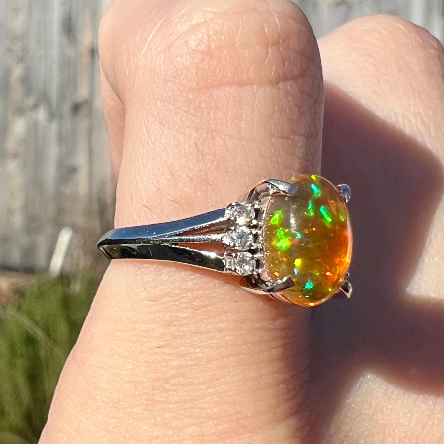 A platinum filigree and diamond-accented Mexican fire opal ring.  The opal is orange with green fire.