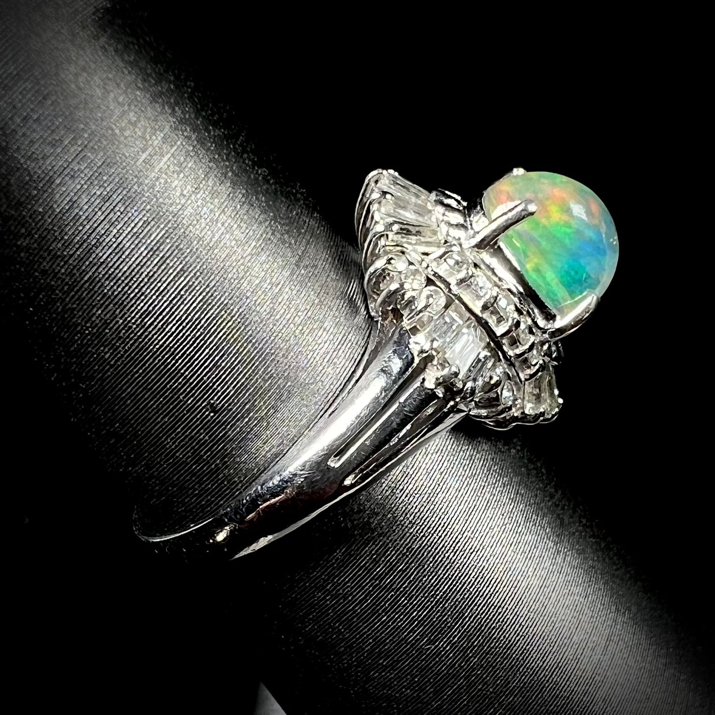 A platinum ring mounted with a Mexican fire opal and baguette cut diamond accents.