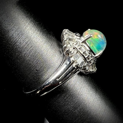 A platinum ring mounted with a Mexican fire opal and baguette cut diamond accents.