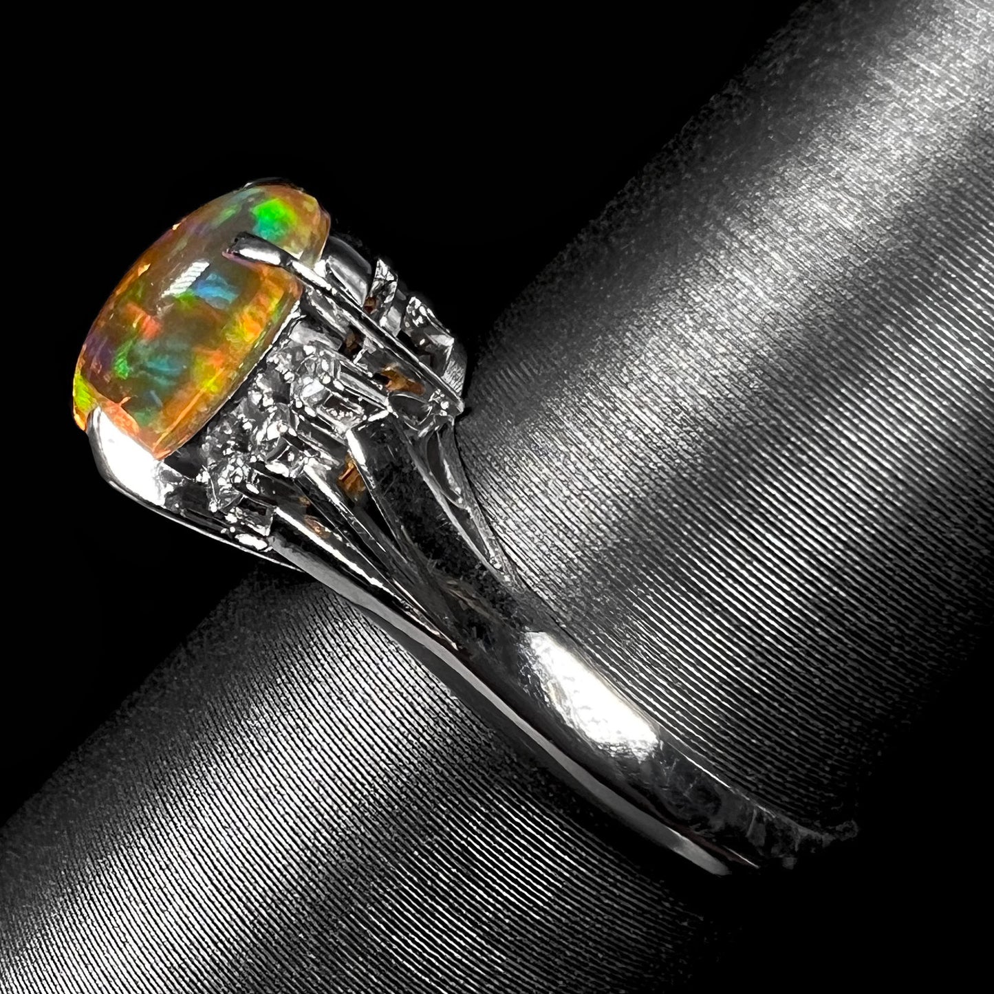 A platinum filigree and diamond-accented Mexican fire opal ring.  The opal is orange with green fire.