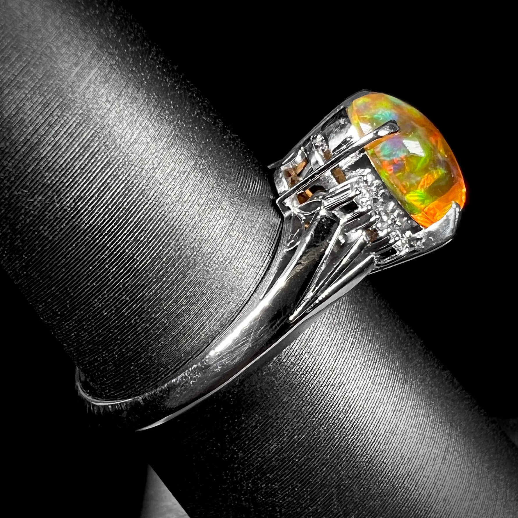 A platinum filigree and diamond-accented Mexican fire opal ring.  The opal is orange with green fire.