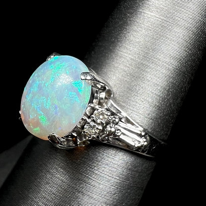 A platinum filigree ring mounted with a blue-green crystal opal and diamond accents.