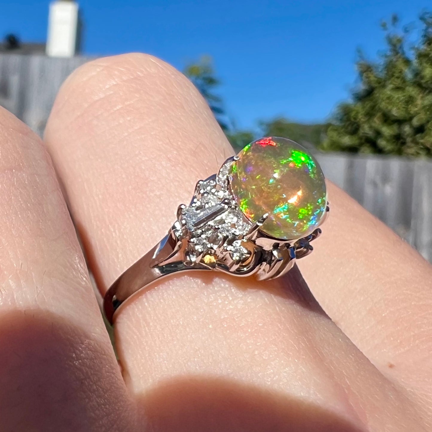 A platinum filigree ring mounted with a high-domed Mexican fire opal and baguette cut diamond accents.