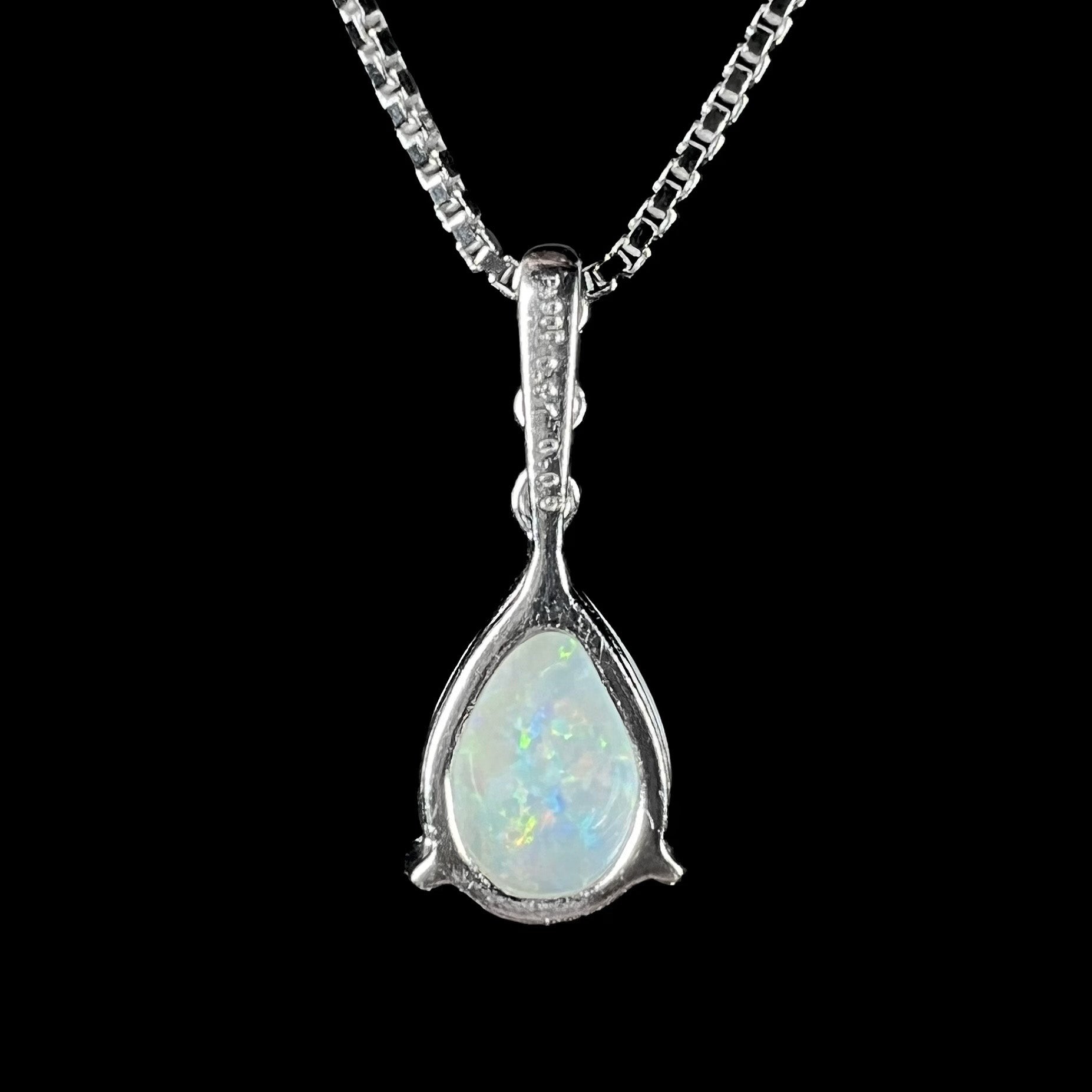 A platinum drop pendant mounted with three diamond accents and a pear shaped opal.