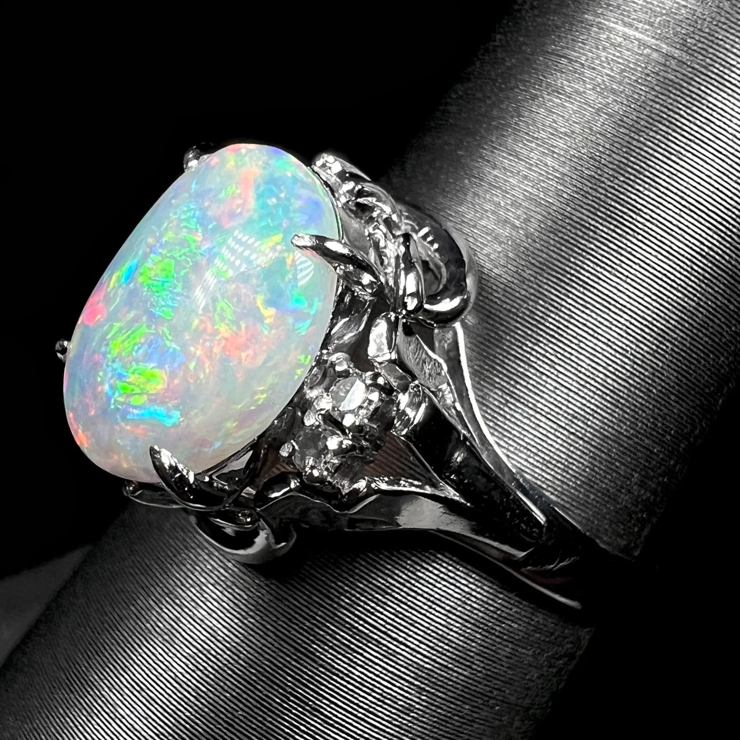 A platinum  and diamond ring prong-set with an Australian opal.  The opal has pink color play.