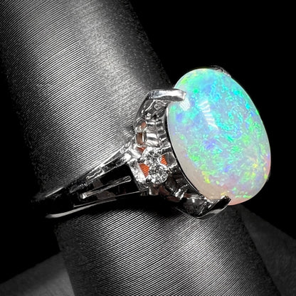 A platinum filigree opal engagement ring set with diamond accents.  The opal has green-blue colors.