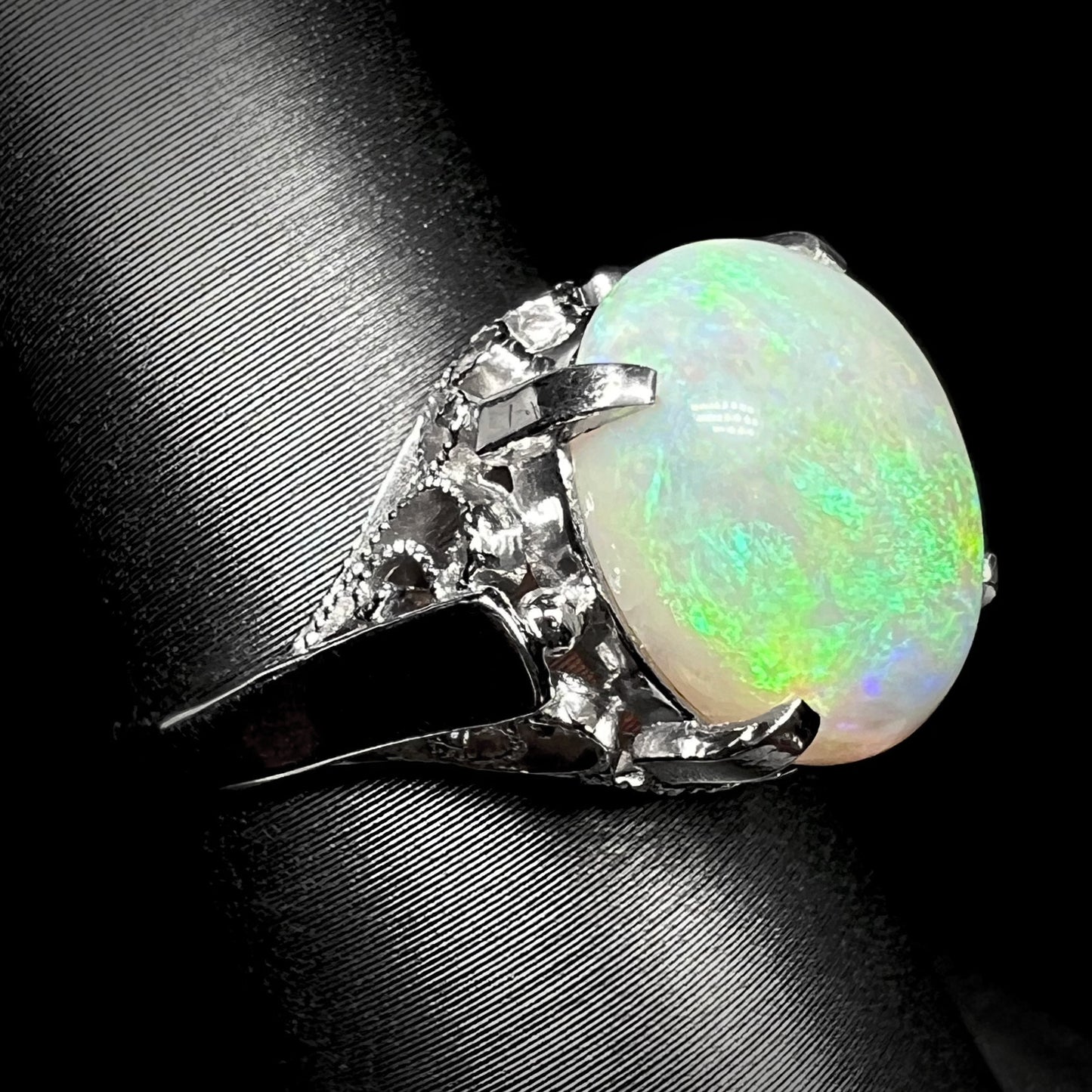 A ladies' Australian opal solitaire engagement ring mounted in platinum.  The opal has green and blue colors.