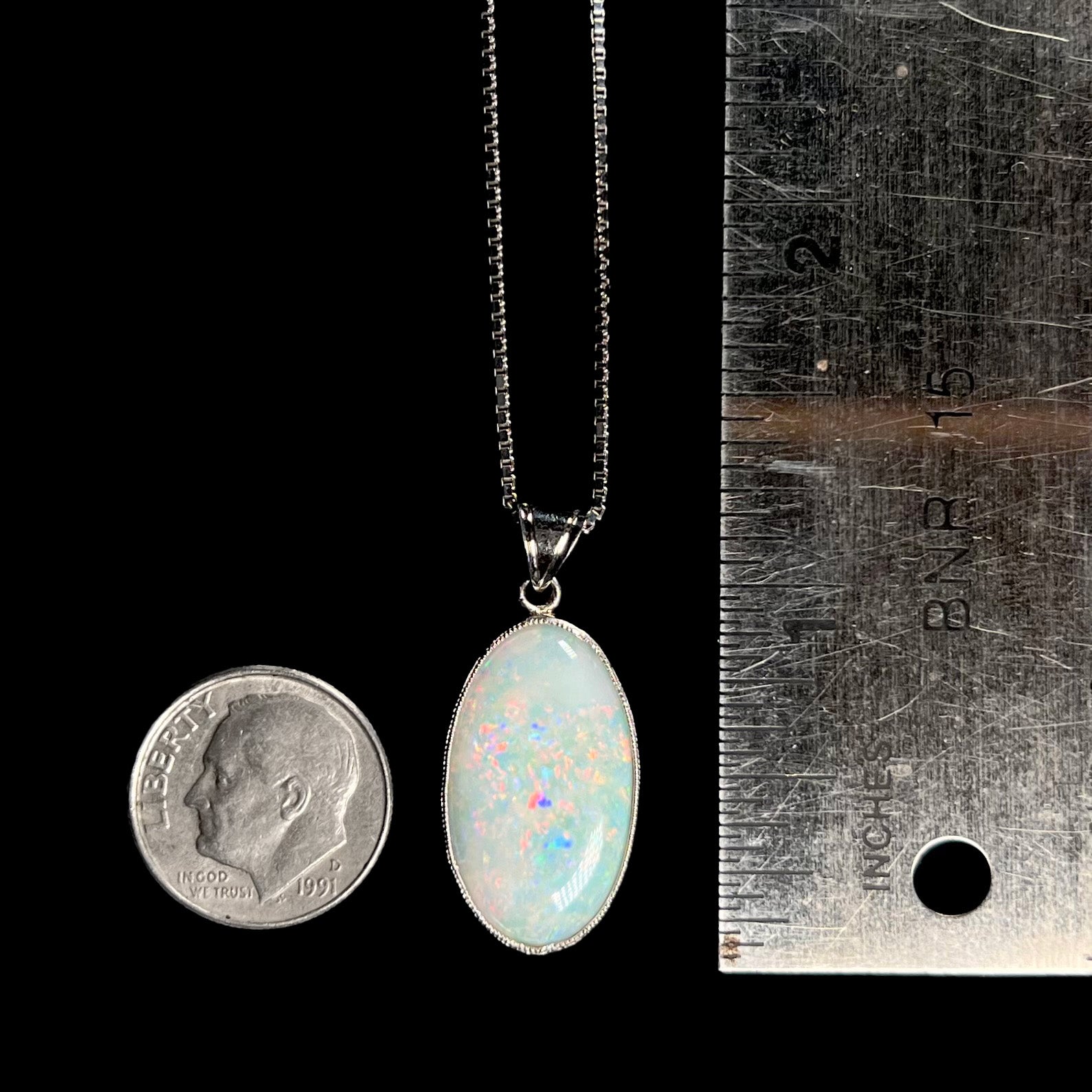 A dime-sized platinum pendant mounted with an oval cut Australian white opal.