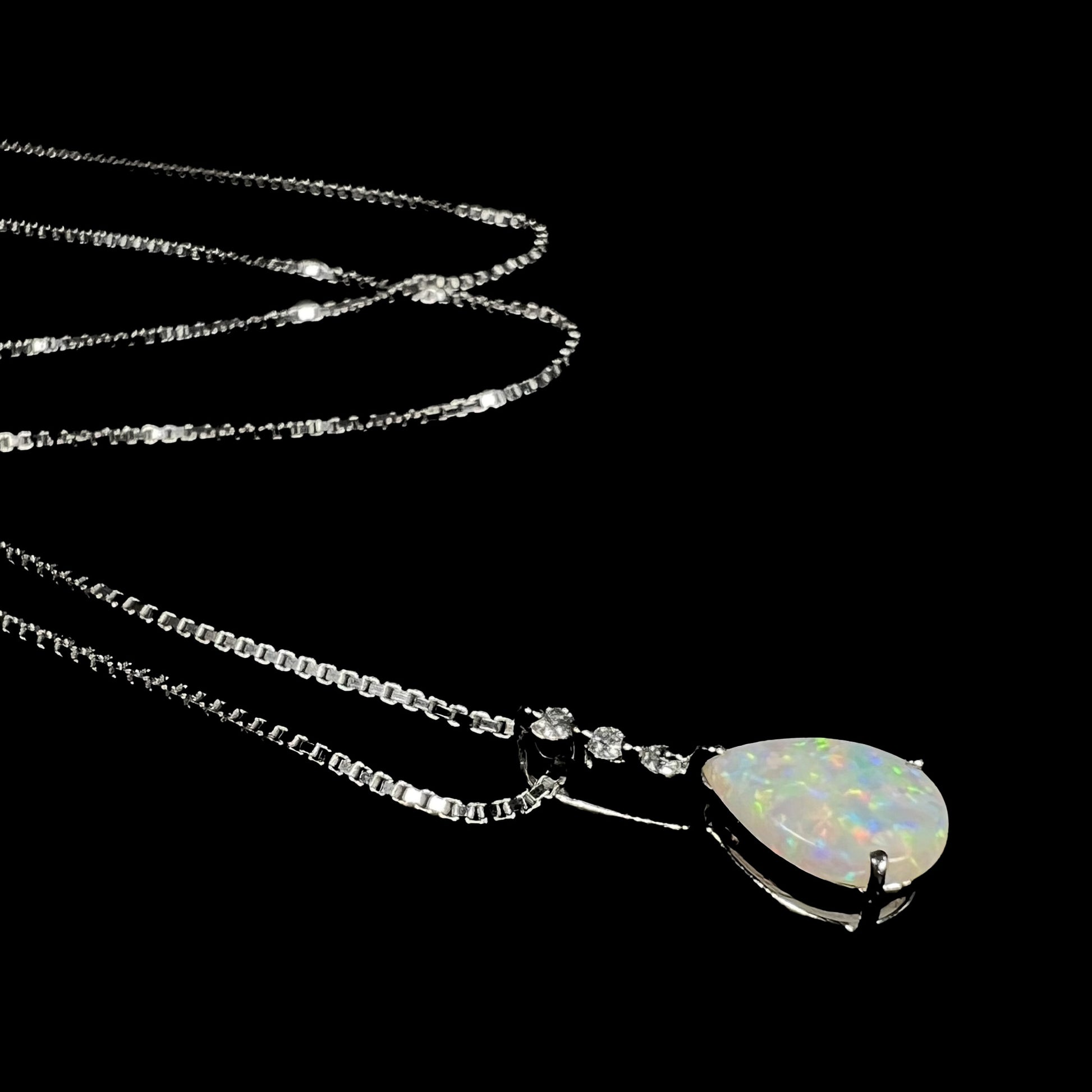 A platinum drop pendant mounted with three diamond accents and a pear shaped opal.