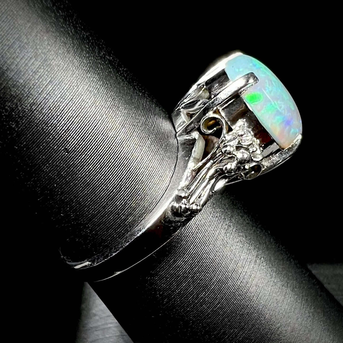 A platinum filigree ring mounted with a blue-green crystal opal and diamond accents.