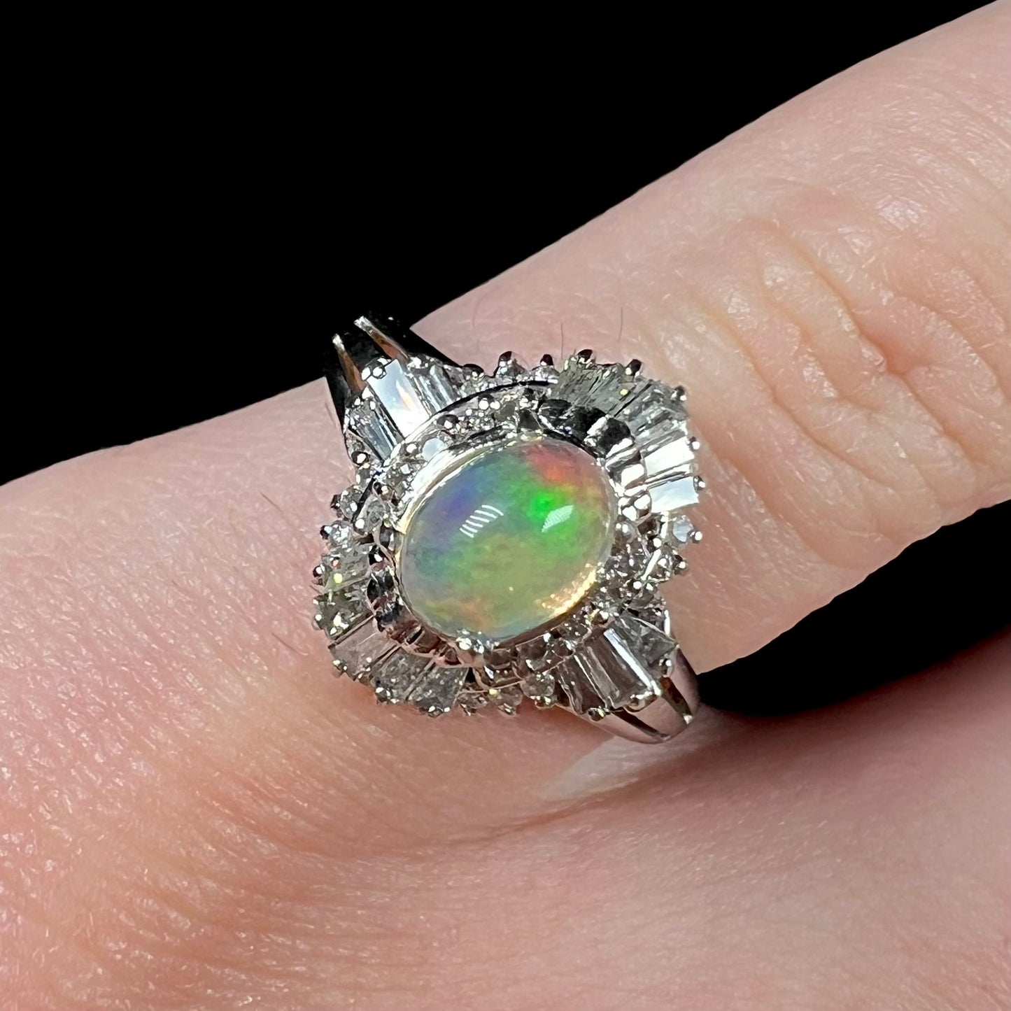 A platinum ring mounted with a Mexican fire opal and baguette cut diamond accents.