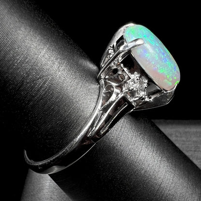 A platinum filigree opal engagement ring set with diamond accents.  The opal has green-blue colors.