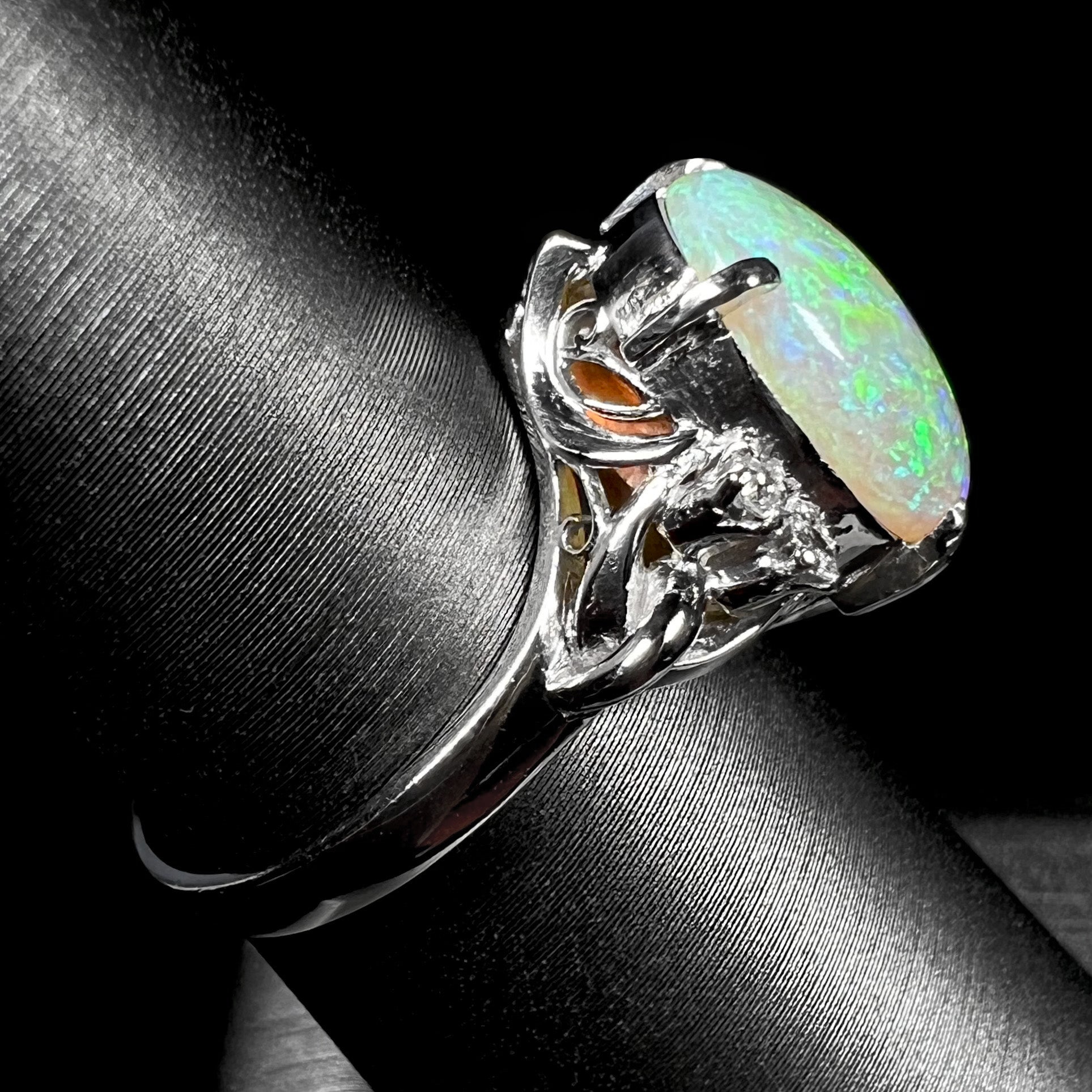 An Australian crystal opal and diamond engagement ring set in a platinum filigree mounting.  The opal plays green/blue colors and has a crack.