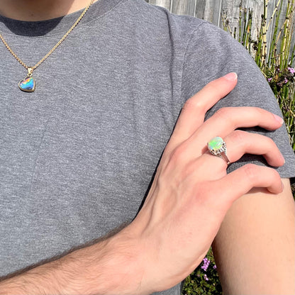 A ladies' Australian opal solitaire engagement ring mounted in platinum.  The opal has green and blue colors.