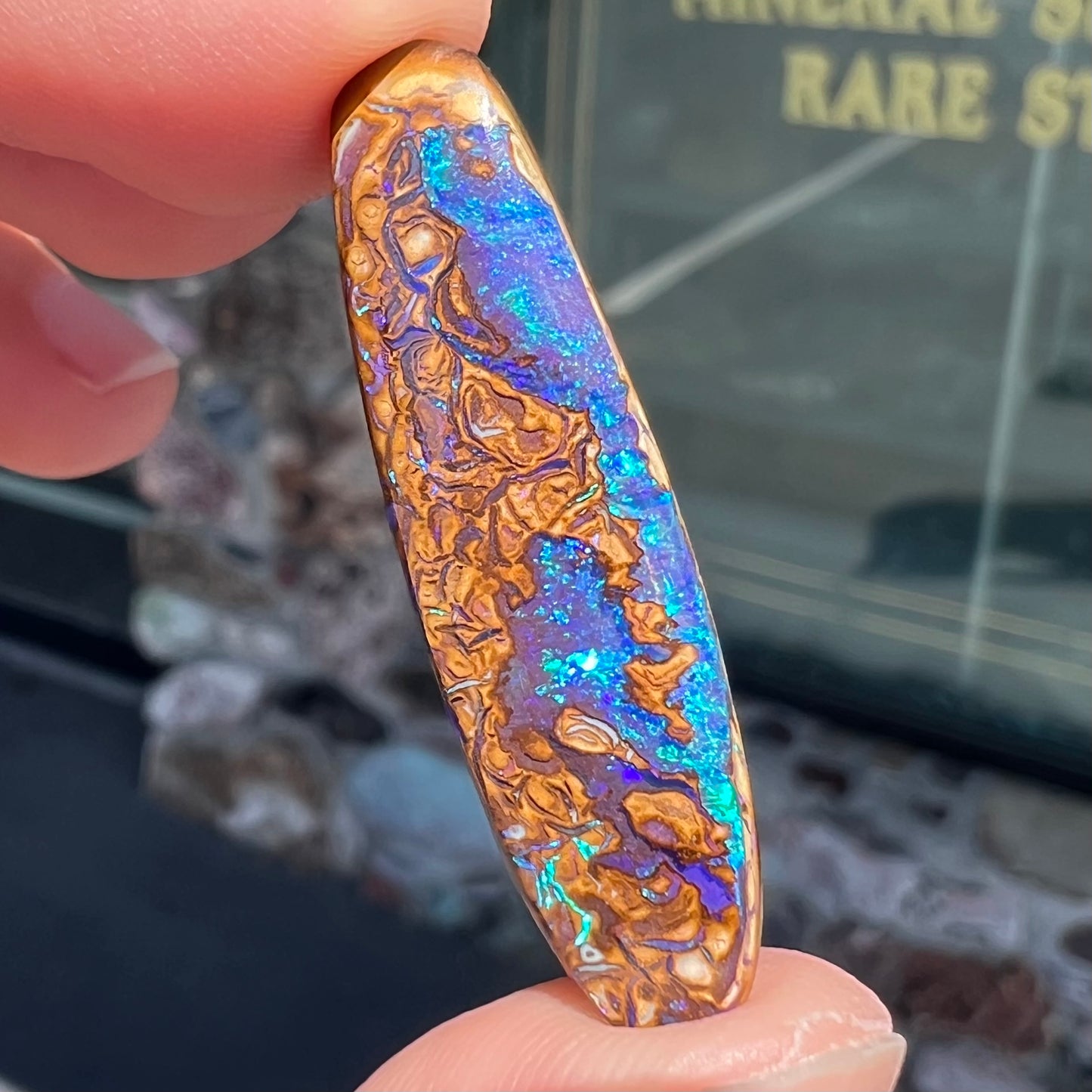 A polished boulder opal stone from Koroit, Australia.  The stone has blue and purple veins.