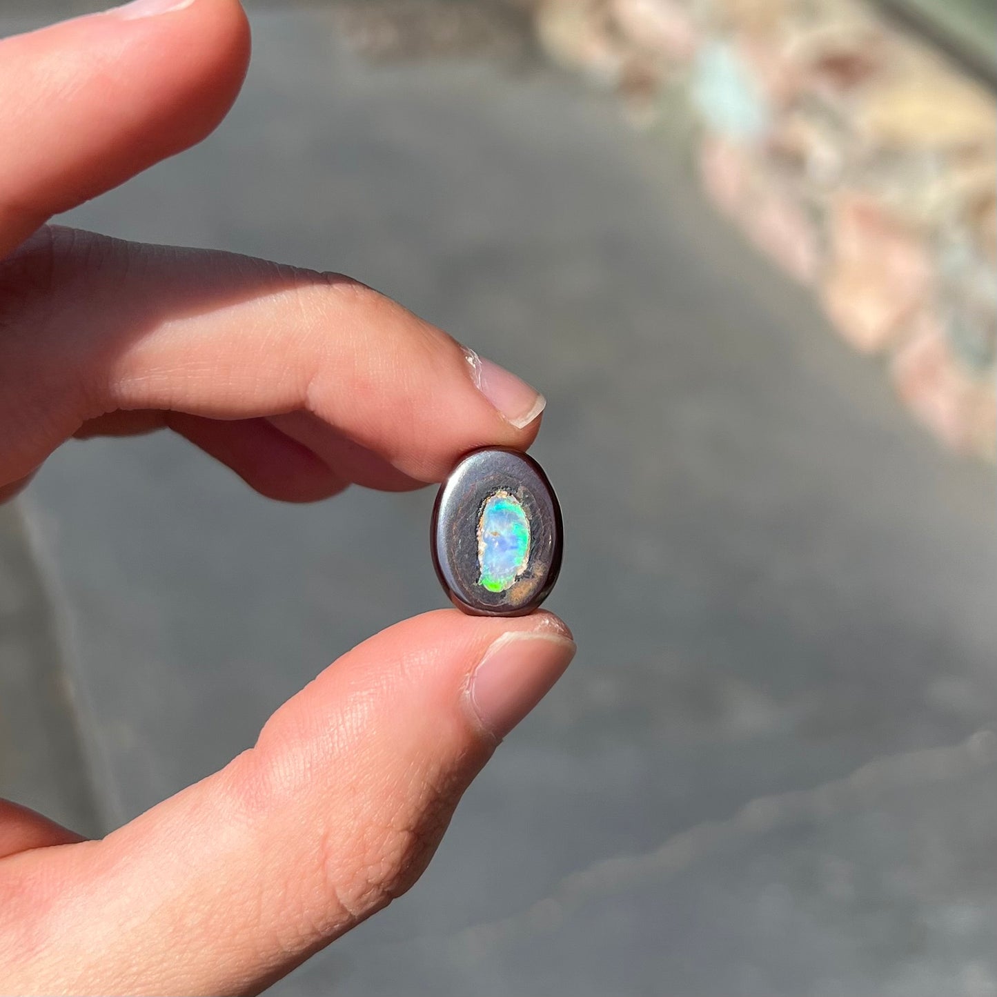 A polished Yowah nut opal stone.  The opal shines blue and green colors.