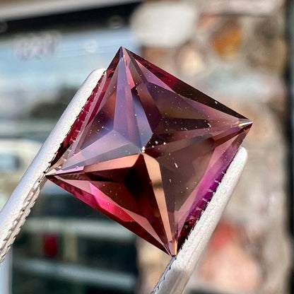 A loose, faceted princess cut tourmaline gemstone.  The stone is a burgundy purple color.