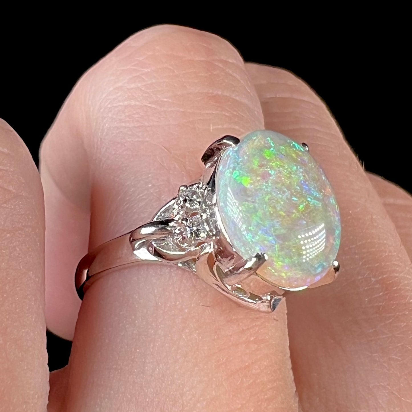 An Australian crystal opal and diamond engagement ring set in a platinum filigree mounting.  The opal plays green/blue colors and has a crack.