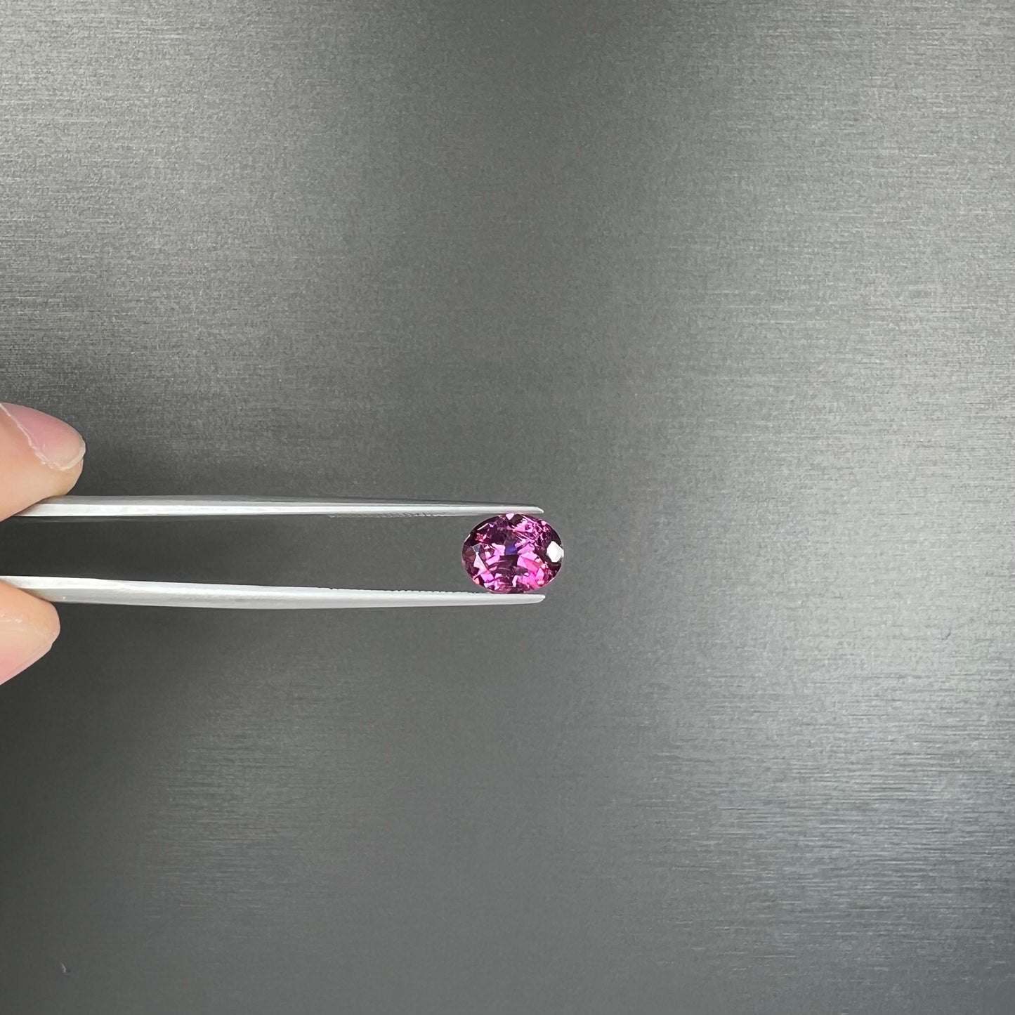 A loose, faceted oval cut purple rhodolite garnet gemstone.