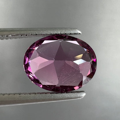 A loose, faceted oval cut purple rhodolite garnet gemstone.