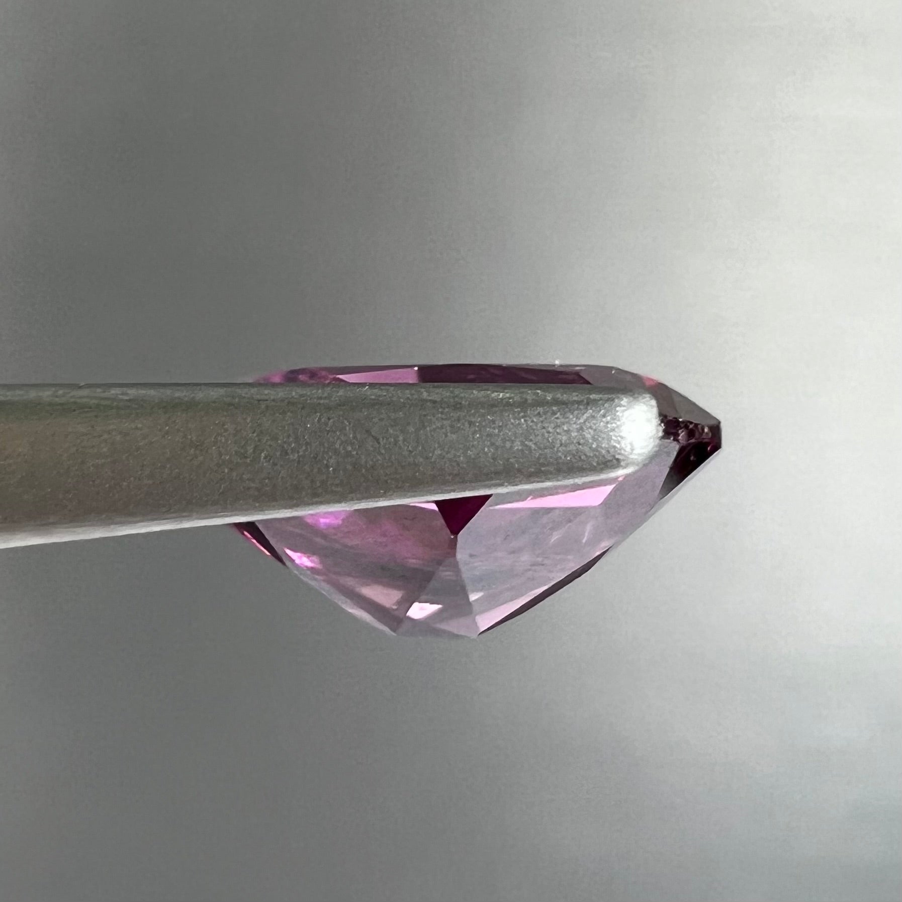 A loose, faceted oval cut purple rhodolite garnet gemstone.