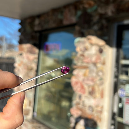 A loose, faceted oval cut purple rhodolite garnet gemstone.