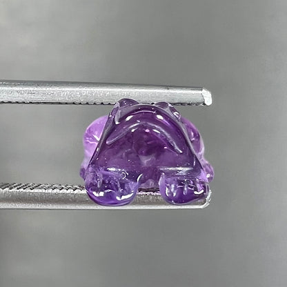 A stone frog carved from purple amethyst crystal.