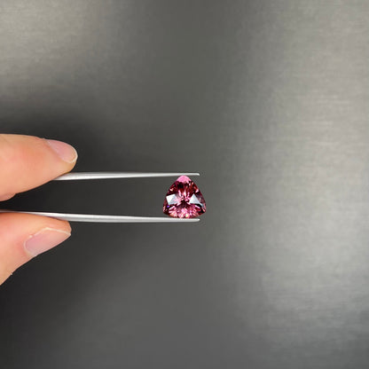 A loose, checkerboard trillion cut purple tourmaline gemstone.